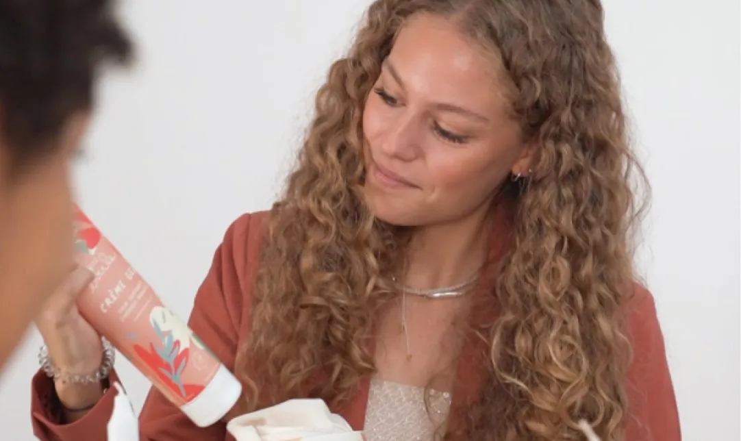 Femme bouclée avec des produits de beauté à la main