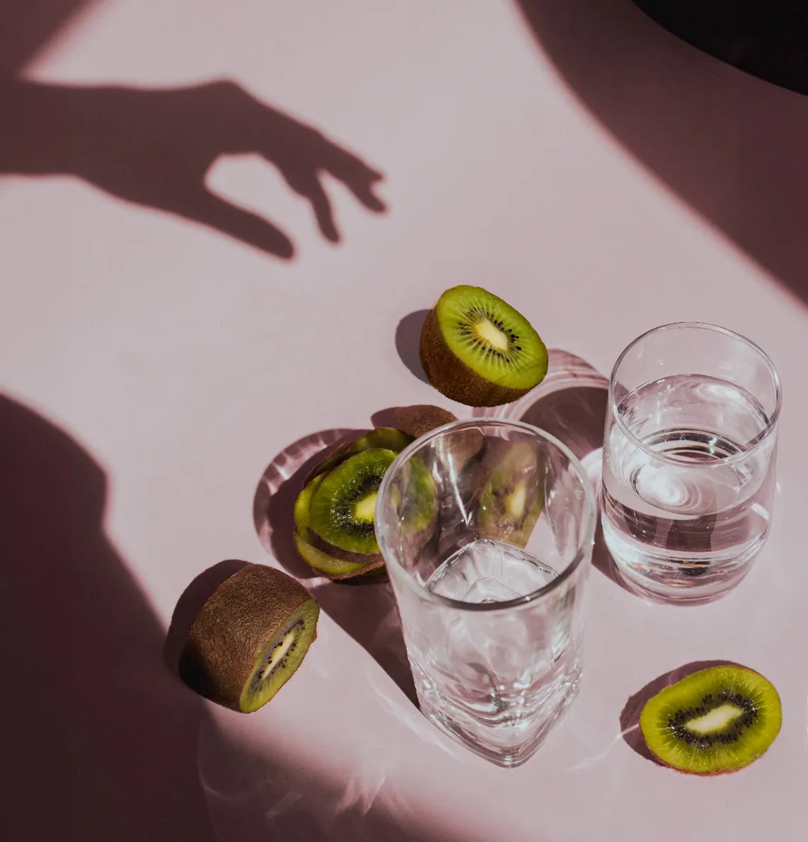 Kiwis et verres d'eau sur un fond rose